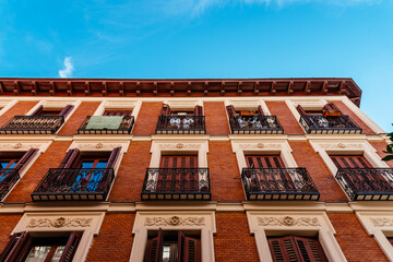 Fototapeta na wymiar Low angle view of old recently renovated residential building against blue sky. Madrid, Spain