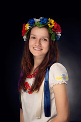 Portrait of smiling caucasian woman wearing traditional Ukrainian wreath with flowers and traditional embroided blouse, vishivanka. 