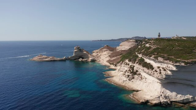 Aerial view of white bluff beach on bay on the coastline with waves in the blue sea. Aerial footage of he immense white cliff on the turquoise sea with boat near Bonifacio Corsica