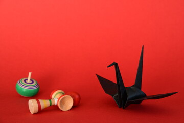Origami crane and spinning tops on red background.