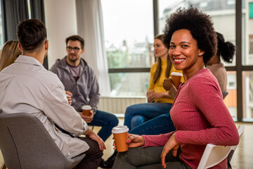 Portrait of woman with diverse group of people sitting in circle in group therapy session.