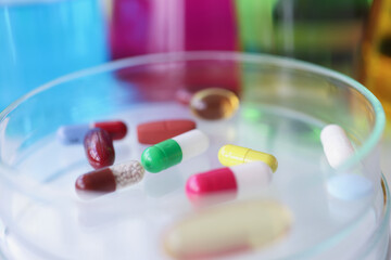Multi-colored medical pills lie on glass test tube closeup