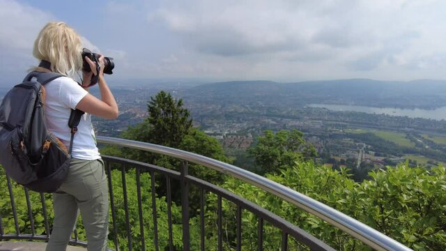Woman photographer taking pictures at Zurich on a Swiss lookout tower in Uetliberg mountain. Swiss plateau of Switzerland in Zurich Canton with its large lake.