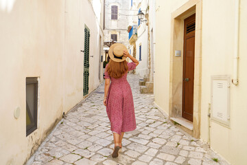 Obraz na płótnie Canvas Back view of pretty tourist woman walking in narrow alley of typical old town of Italy