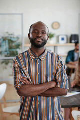 Portrait of African young businessman standing with arms crossed at office and looking at camera