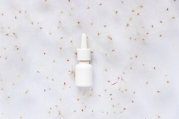 A mock-up of a nasal spray on the background of dandelion seeds. The concept of seasonal allergy.