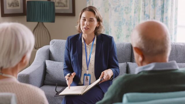 Social worker talking to senior couple at home