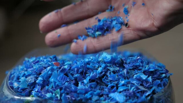 Female hand iterating blue plastic pieces lying in a transparent container 