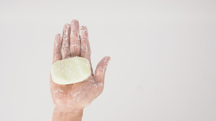 Hands washing gesture with bar soap and foam bubble on white background.