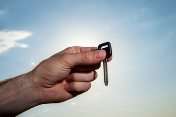 Female handing over keys on dramatic clouds and sky with sun rays behind.