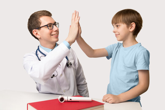 Children's practicing caucasian doctor with a boy patient on a white background. Smiling people cheerfully make High five. Healthy childhood, the concept of pediatrics and modern successful treatment