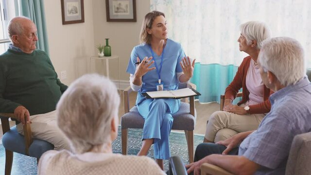 Nurse talking to senior people during group therapy