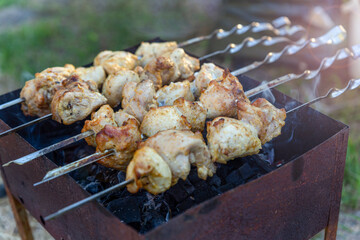 Skewered meat is fried on charcoal close-up on a grill or brazier. Picnic, evening with friends and family, cooking over an open fire in the front or backyard. Charcoal grill.