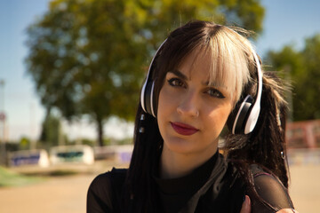 Portrait of young and beautiful girl with heterochromia, pigtails, white headphones and punk style...