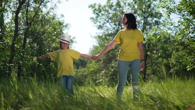 Happy family. Mom and daughter in forest park. People walk on grass. Happy team mom and daughter. Family is walk on grass in park. People walk along the tava in forest. Happy family concept