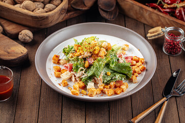 Russian malibu salad with croutons and ham on wooden background