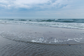 Baltic Sea coast in Poland, waves, sea foam, sky and beach