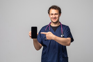 Young doctor showing a phone and pointing on white background