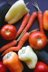 Zucchini, tomatoes, peppers, carrots and cucumbers on dark background. Flat lay.