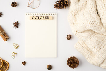 Obraz premium Top view photo of white scarf notebook with inscription october pine cones dried lemon slices cinnamon sticks golden binder clips and stylish glasses on isolated white background with blank space