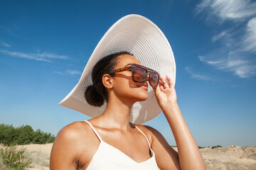 dark-skinned woman in sunglasses walks along the sand in the desert in the summer