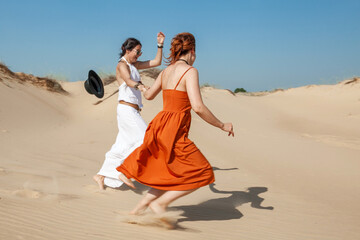 Fototapeta na wymiar two women walk on hot sand in the desert in the summer
