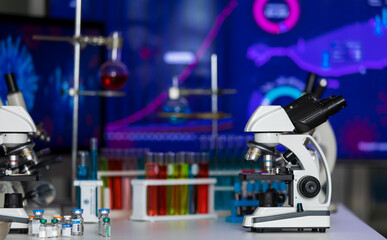Microscope in dark laboratory with several medical tube and vial bottle for vaccine experiment and research