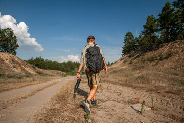 Naklejka premium a man walks along the road leading to the forest in the summer