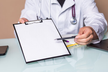 Smiling male doctor holding clipboard offer for sign at office desk