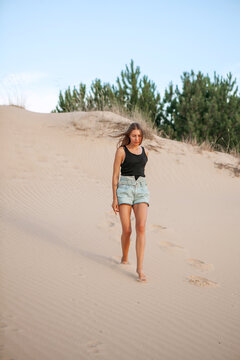 woman in shorts stroll along the sand of the desert in the summer