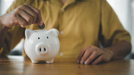 businessman hand putting coin in piggy bank. Saving money concept, business finance and investment..