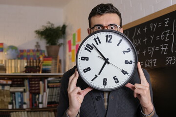 Teacher holding large clock in classroom