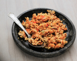 Selected Focus Sambal Tempeh, Spicy Crushed Tempe on Stone Pestle. Traditional Indonesian Food with Spicy and Savory Taste