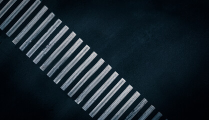 White stripes of paint on empty pedestrian crossing: designation of a pedestrian crossing. An empty pedestrian crossing on the black asphalt road of the street. Aerial top view shot. Road Background.