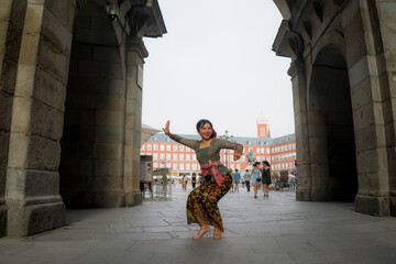 young happy and beautiful Asian woman wearing traditional Balinese kebaya dress - Indonesian girl doing Bali dance on street during holidays travel in Europe