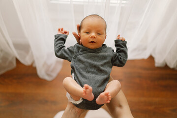 Mother holds and hugs her newborn baby son at home. Happy infant and mom.