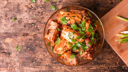 Cooking pork ribs - raw chopped pork ribs marinated in a hot sauce with fresh basil in a bowl on...