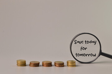 Stack of coins and magnifying glass written with SAVE TODAY FOR TOMORROW