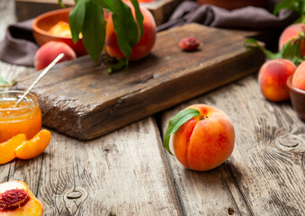 Still life peaches on wooden table with cutting board knife in dark key. Juicy ripe peaches on dark wooden rustic table. Delicious farm peaches with leaves whole fruit in halves, peach with bone