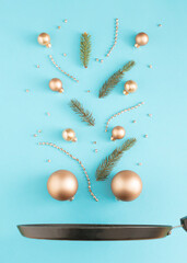 Fototapeta premium Christmas baubles with pine branches above the pan. Minimal New Year decoration concept. Flat lay background.