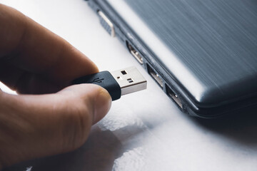 Hand inserting USB (Universal Serial Bus) Type A version 3.0 connecting to usb port of laptop