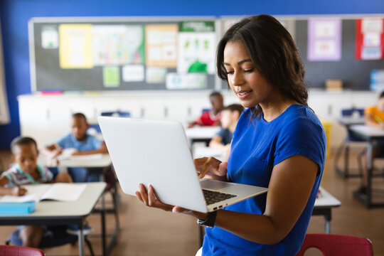 African american female teacher using laptop in the class at school