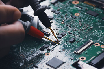 Technician checking laptop circuit board with multimeter