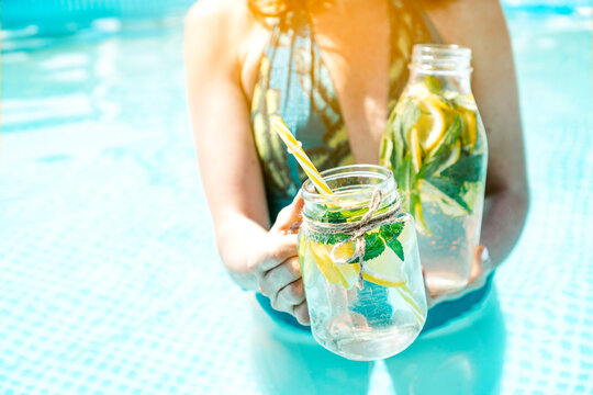 Cold lemonade in female hands by the pool