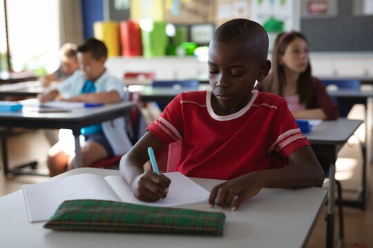 African american boy studying while sitting on his desk in the class at school