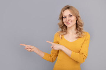 cheerful blonde beauty woman with curly hair pointing finger on copy space, advert