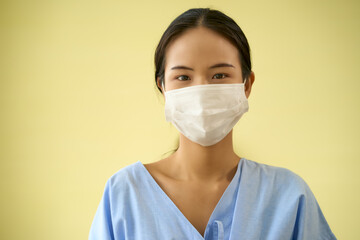 Asian female with face mask portrait on yellow background
