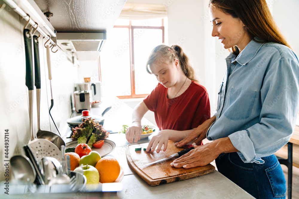 Wall mural White woman and her daughter with down syndrome cooking salad