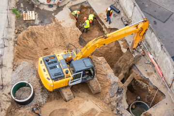 Excavator at a construction site while digging trenches for calcining sewer and drainpipes with a...