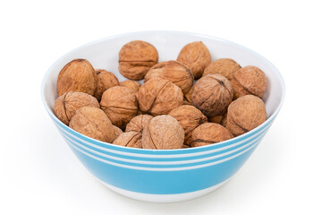Unshelled walnuts in blue bowl, close-up in selective focus